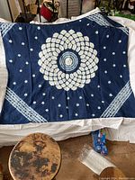 Full view of the blue fabric square laid out showing central floral pattern and smaller scattered floral motifs