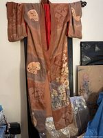 Front view of vintage kimono hanging that shows its overall length, wide sleeves, and color pattern.