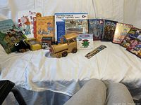 Photo showing assortment of children's books, toys, DVDs, and table tennis set on white cloth.