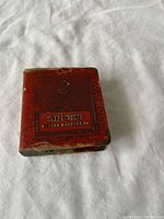 Front view of the vintage Singer sewing machine coin bank in red leather book style showing the embossed Singer Sewing Machine Co. logo and worn edges.