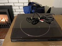 Black Pioneer PL-990 stereo turntable with attached power and audio cables on top, resting on table.