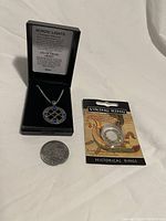 Photo showing the pendant necklace in a black box with info card, two Viking rings in original packaging, and a quarter for size reference.