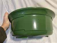 Side view photo showing the green ceramic bowl with stepped geometric pattern and hand for scale.