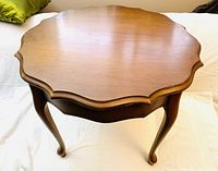 Top view of the round wooden coffee table showing scalloped edges and smooth tabletop surface.