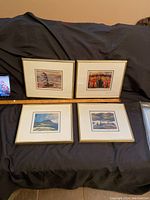 Four framed art cards arranged in a grid on black fabric background with a ruler for scale, showing size and framing style.