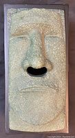 Front view of textured ceramic Easter Island Moai face dispensing tissues through nose opening.