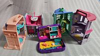 Wide photo showing all three playsets: Fisher Price Sweet Street Toy Shop, Dance Studio, and Polly Pocket backpack open revealing beach scene