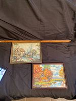 Both framed needlepoint embroidery pieces placed next to a wooden ruler for scale, showing approximate size 12x9 inches each.
