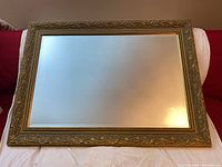 Front view of the gilt framed bevelled mirror showing gold ornate detailed frame and bevelled edges of glass.
