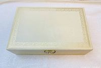Closed view of ivory jewellery box with gold decorative border and clasp