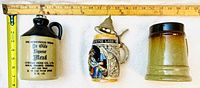 Top view of three vintage vessels including a jug, a beer stein, and a mug with ruler for scale.