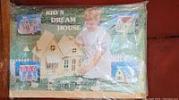 Box front showing wooden dream house kit with images of completed house and a child assembling it.