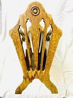 Front view of vintage wooden magazine rack showing carved design, cut-out shapes, and circular detail on top.