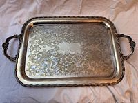 Top view showing ornate handles and detailed floral and scroll engraving on surface with scalloped edges.