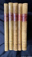 Five antique British Columbia Statutes books standing upright side by side showing vellum spines with red title labels.
