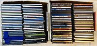 Two cardboard boxes filled with many audio CD jewel cases stacked vertically and horizontally.