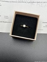 Ring displayed in presentation box with appraisal certificate visible in background