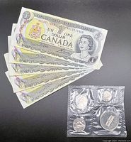 Five 1973 Canadian one dollar bills in good condition with a set of four uncirculated 1973 Canadian coins in sealed packaging.