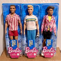 All three Barbie 60th Anniversary Ken dolls in original packaging shown together.