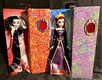 Both dolls in their open internal boxes showing Cruella DeVil on the left and Evil Queen on the right with designed boxes featuring respective villain imagery.