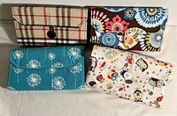 Four handmade wallets and coin purses arranged on a flat surface showing front flap designs and closures.