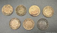 Seven large Canadian one cent coins arranged in a group, dated from 1910 to 1920, each showing the reverse side with maple leaf wreath and date.