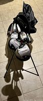 Top angled view of the black and gray golf bag containing multiple golf clubs with silver heads and black and red shafts, showing bag upright with open top
