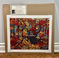 Full view of the art print attached to cardboard backing, showing the colorful autumn forest scene with the pool, the artist bio card above and corner protectors.