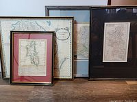 Four framed antique maps grouped together showing varying sizes and framing styles.
