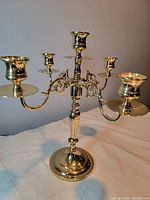 Front and side view of brass candelabra showing five candle holders and polished finish.
