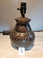 Handmade ceramic Latin American design lamp with visible geometric and spiral patterns on ceramic body, set on a dark wood base with felt pad. Lamp socket and fitting included, no shade present.
