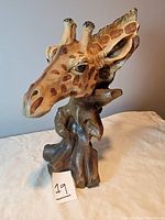 Front-left angle view of the resin giraffe head sculpture showing natural giraffe color patterns and wood-like base.