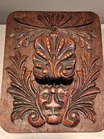 Front view of hand carved wooden wall art showing human face and floral pattern.