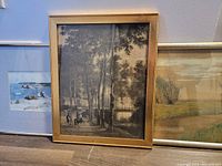 Framed black and white hunting scene print showing tall trees and riders on horses, light wood frame