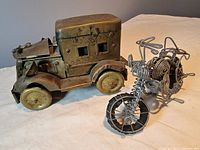 Side and front view of antique stamped brass jalopy and wire motorcycle models on display.