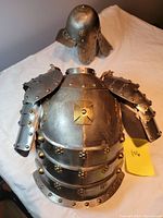 Front view of the articulated breastplate and separate helmet showing the layered metal plating and rivet details.