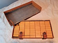 Overhead view of open box containing neatly stacked butterscotch-colored playing card tiles, showing box condition and tile arrangement.