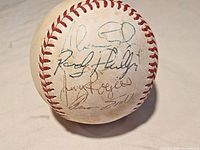 Top view of the baseball showing five player signatures in black ink on white leather surface with red stitching.