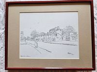 Framed black and white line art print depicting a streetscape in Sydenham, Ontario. Includes signature and number 40/200 by Shirley Gibson-Lanille dated 1991. Shown wired and ready for hanging.