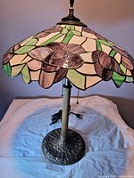 Full view of Tiffany-style lamp showing stained glass floral shade and brass base on white background.
