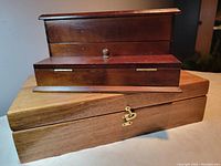 Wooden storage boxes stacked on each other showing brass latch and knobs.