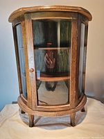 Curved glass front and side panels with wooden door and knob shown, illustrating cabinet design and glass details