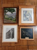 Four wooden frames with different artworks displayed on floor.