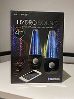 Front of the product box showing the product name, image of two speakers with water jets and 4 color LED lights, and Bluetooth logo.