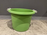 Side view of green plastic storage bin showing shape and rope handles