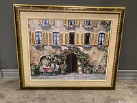 Front view of framed wall art showing detailed scene of European street cafe with tables, chairs, flowers, and bicycle.