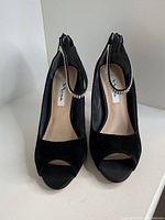 Front view of both black high heel shoes showing open toe and rhinestone ankle straps.