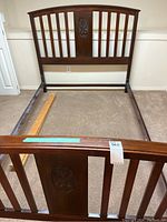 Full view of antique double size wooden bed frame showing headboard with carved decorative center panel and footboard with similar design