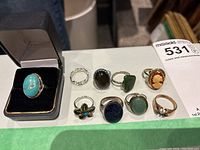 Top view showing the full assortment of 9 rings including one in a presentation box and other varied designs and stone colors.