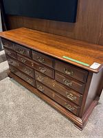 Overall view of wood dresser showing nine drawers and wood finish.
